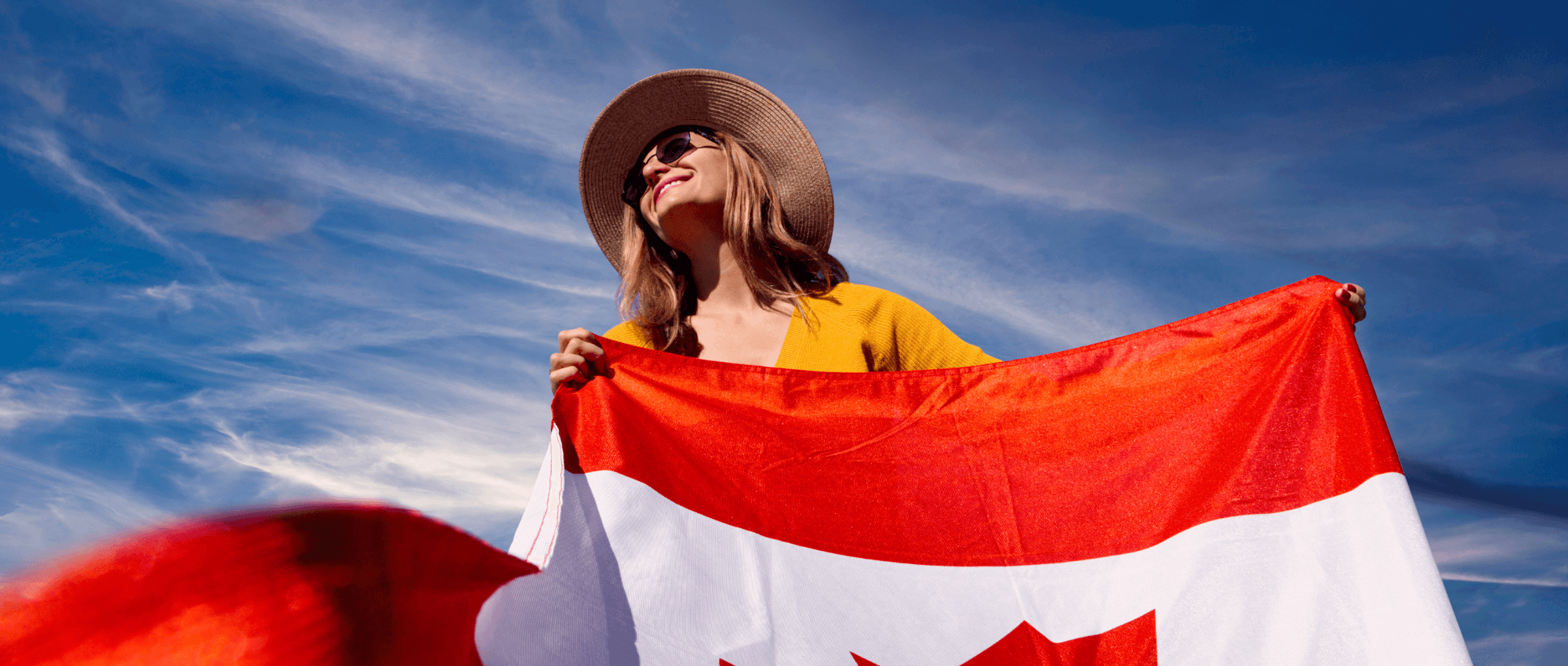 woman holding canada flag against blue sky