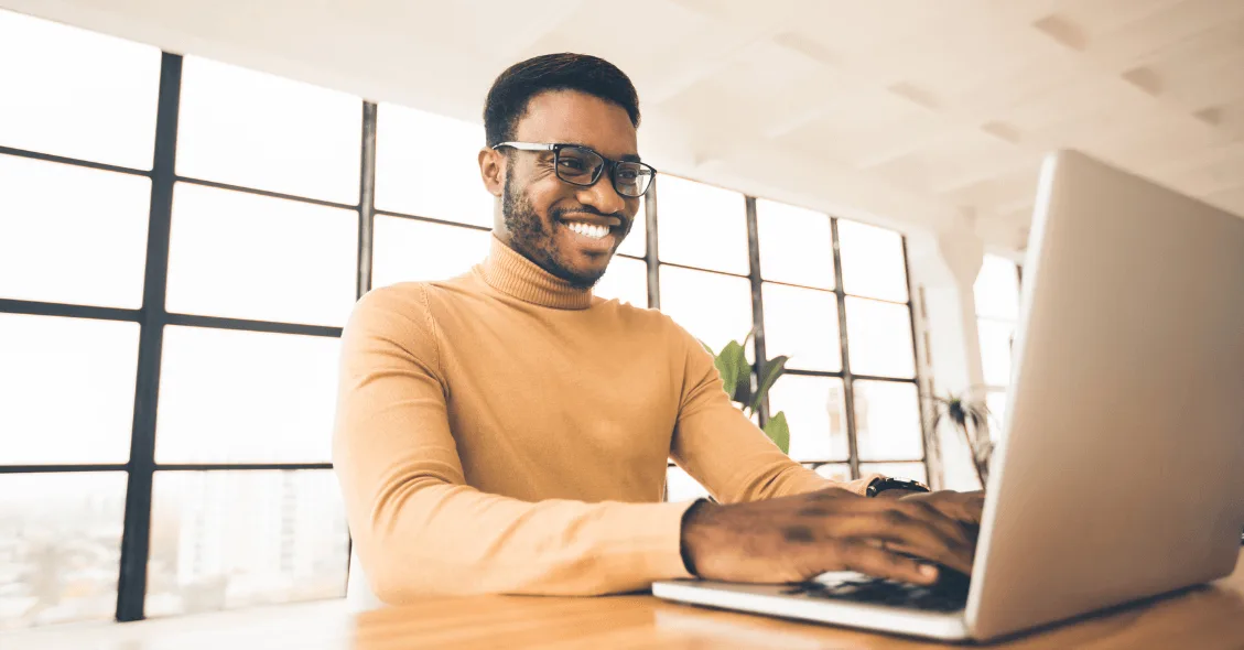 man smiling in front of a laptop